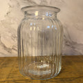 Clear glass jar on a wooden surface with a marble-patterned wall in the background